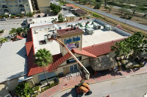 Hotel building with a red tile roof between palm trees